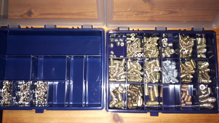 Två Raaco förvaringsboxar öppna med ordnat innehåll av skruvar och muttrar på ett träbord.