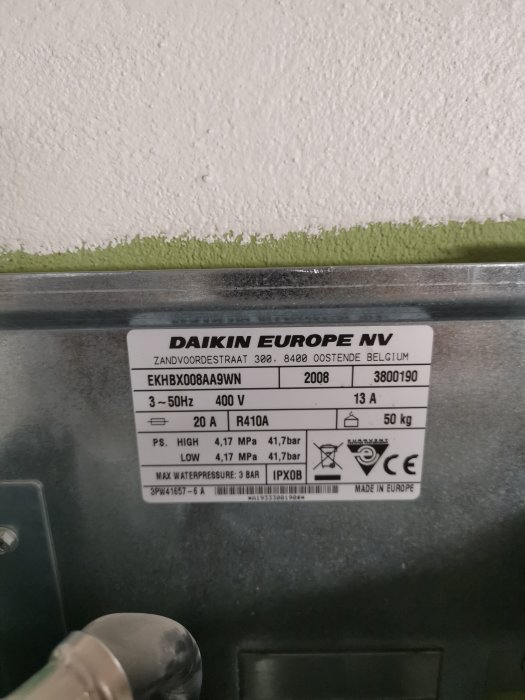 Etikett på en Daikin värmepump med tekniska specifikationer på en grå bakgrund.