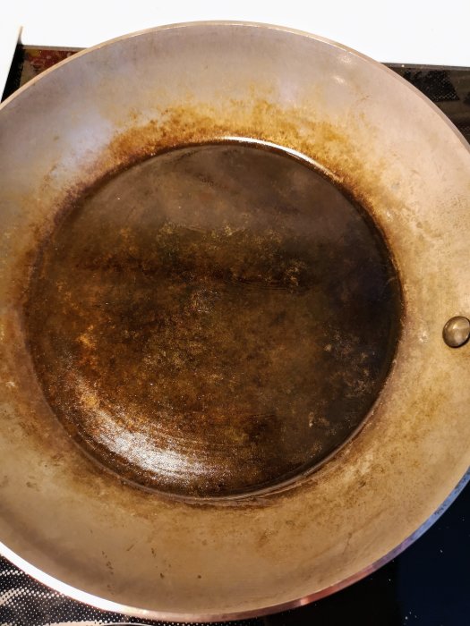 Väl instekt De Buyer kolstålstekpanna med patinerad yta som illustrerar användning och non-stick-kvalitet.