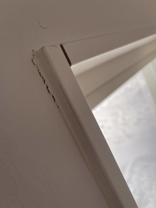 Sprickor i hörnet av en vitmålad dörrkarm i ett nybyggt hus.