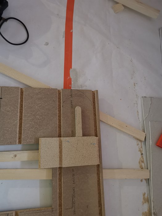 Trämall för fräsning placerad på ett skyddsplastat vardagsrumsgolv med byggmaterial.