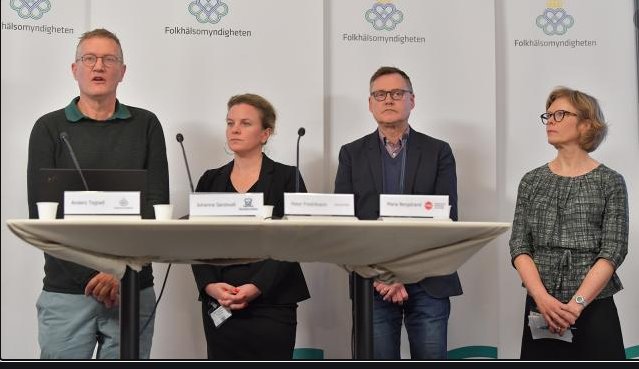 Fyra personer står bakom talarpult med mikrofoner; en ser längre ut pga perspektiv.