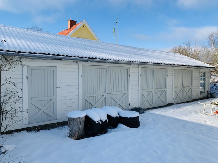 Vit lada med hembyggda dörrar med Z-mönster i snöigt landskap, med svenska flaggan i bakgrunden.