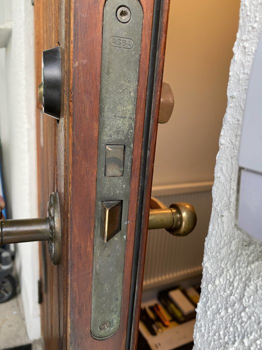 Närbild av ett gammalt ASSA lås på en dörr med dörrhandtag och nyckelhål synliga.
