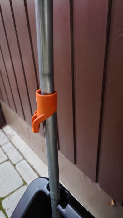 Orange låsning på ett grått snöslädestag mot en brun bakgrund.