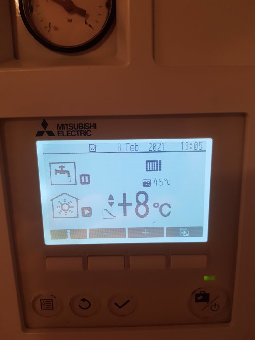 Display av Mitsubishi värmepump som visar inställningar och temperatur på +8°C, intill ett tryckmätare.