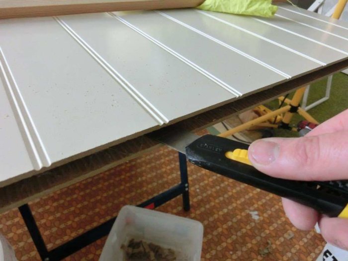 En person kapar en vit garderobsdörr, markerad med en kniv för precision.