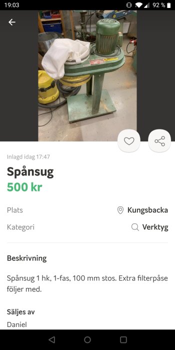 Spånsug i en verkstad med en extra filterpåse på toppen, samt dammsugare och verktyg i bakgrunden.