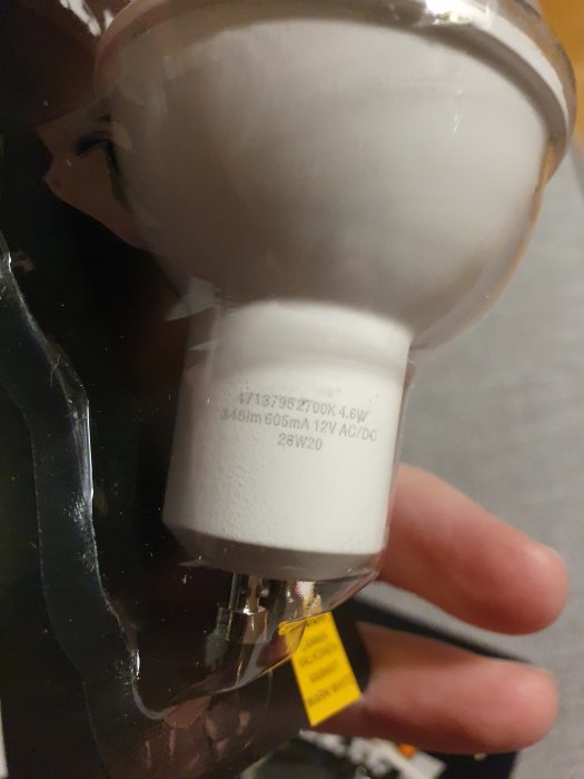 Hand som håller en GU10 LED-lampa med tekniska specifikationer synliga på dess vita kropp.