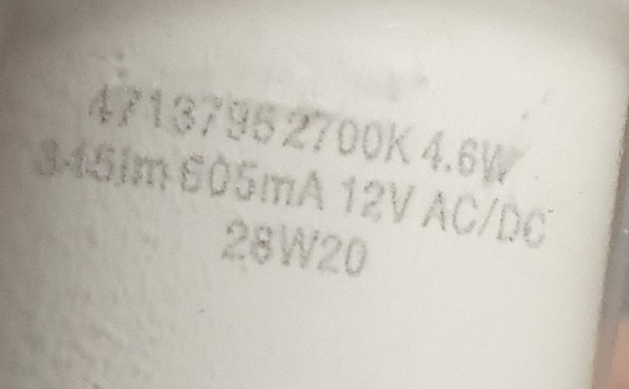 Närbild av specifikationsmärkningen på en 12V GU10-lampa som visar 605mA och 2700K färgtemperatur.
