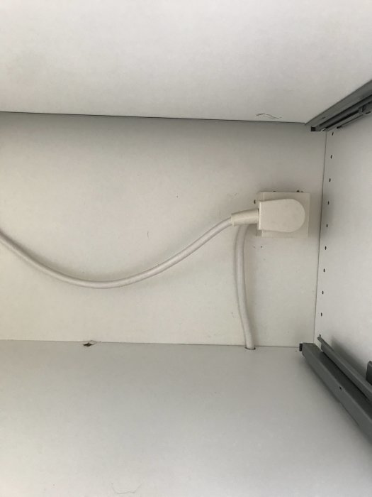 En Perilex stickkontakt monterad på vägg ovanför köksbänk med ansluten vit elkabel.