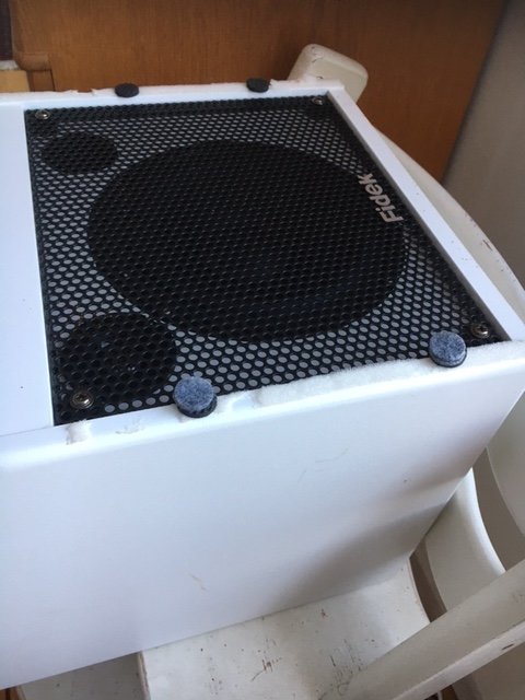 Högtalarhölje med möbeltassar placerade i hörnen på vit yta för att dämpa resonansfrekvensen.