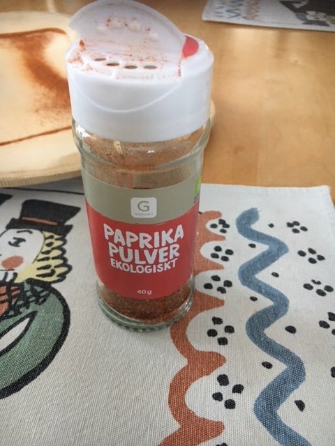 Burk med ekologiskt paprikapulver på ett mönstrat tyg.
