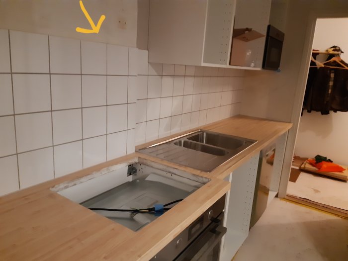 Kök under renovering med väggtill-vägg skarv ovanför diskbänksdel, pil pekar på skarven.