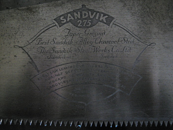 Närbild av ett sågblad med Sandvik 275 ingraverat och text om Sandvik Alloy Charcoal Steel från Sverige.