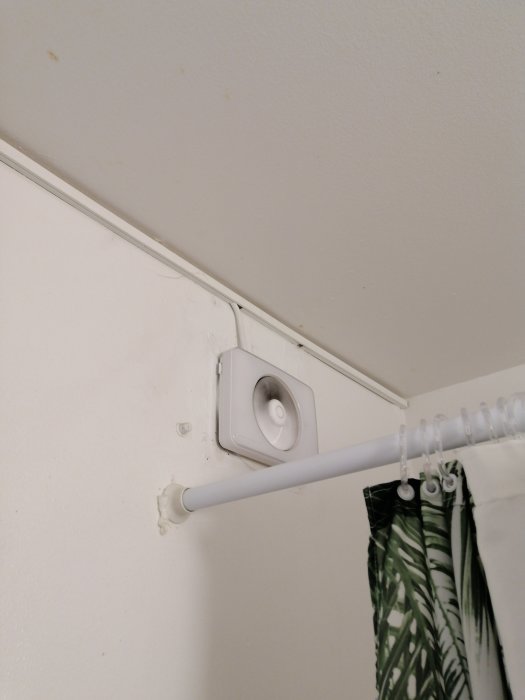 Mögelpåväxt i kakelfogen i ett hörn av en badrumsdusch med gardinstång och ventilation.