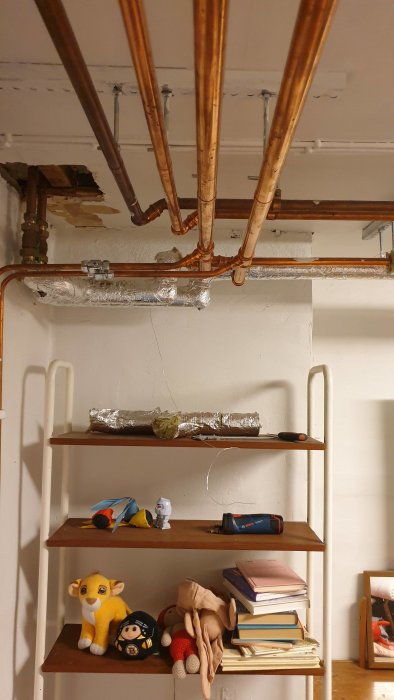 Kopparrör i taket med isolering, skillnader synliga mellan gamla och nya delar, på hylla under.