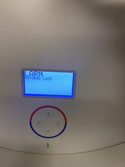 Värmepumpens kontrollpanel med felmeddelandet "Larm motorsk löst" visas på skärmen.