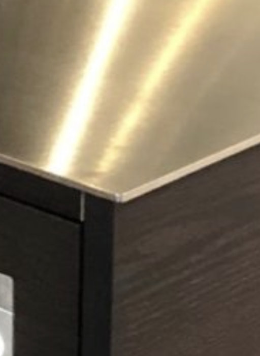 Metallkant på underlimmat köksbänksmaterial i restaurangkök som jämförs med laminat och massivt trä.