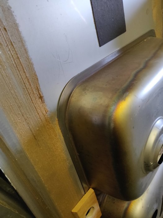Rostfri hetvattenvärmare monterad intill isolerad vägg med synlig isolering.