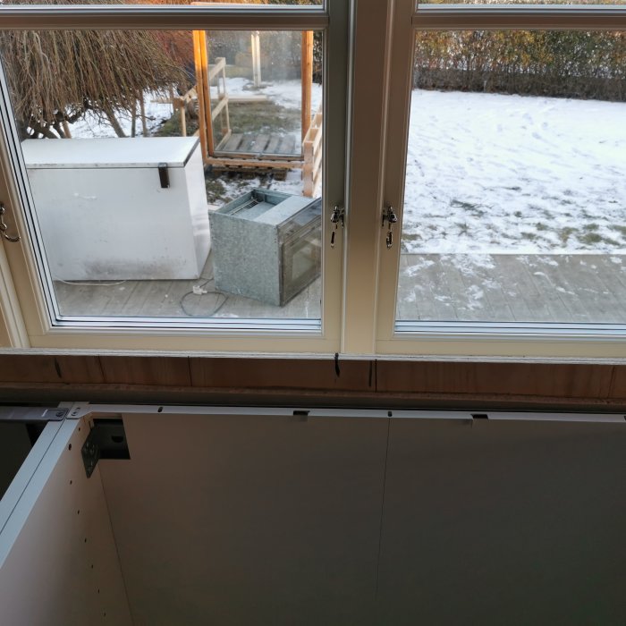 Kök med bänkskåp framför ett fönster, markerat med linje för mitten, i ett hem under renovering.