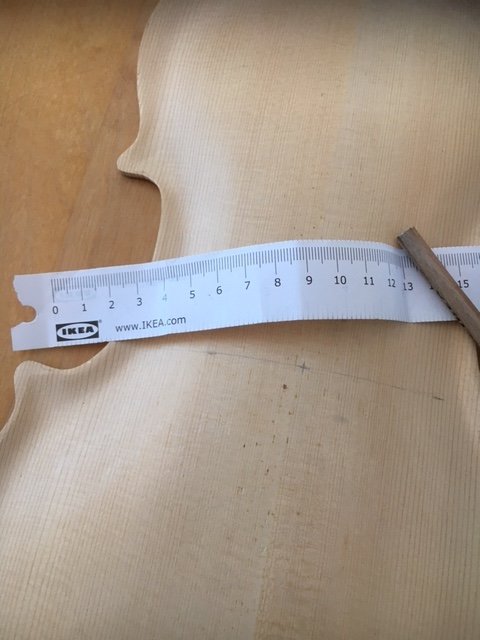 Otydliga blyertsmärken och en böjlig IKEA-linjal på ett träinstrumentlock vid utmärkning för F-hål.