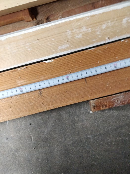 Måttband ligger på trämaterial vid mätning nära 70 centimeter-märket.