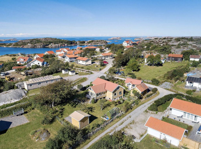 Flygbild över kustnära sommarparadis med traditionella hus och havsutsikt.