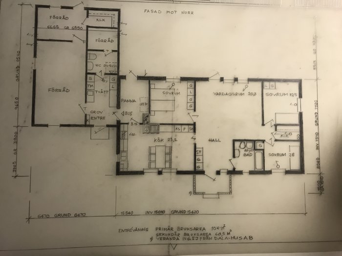 Handritad planritning av ett hus med tydligt märkta rum och dimensioner, inklusive vardagsrum, kök och sovrum.