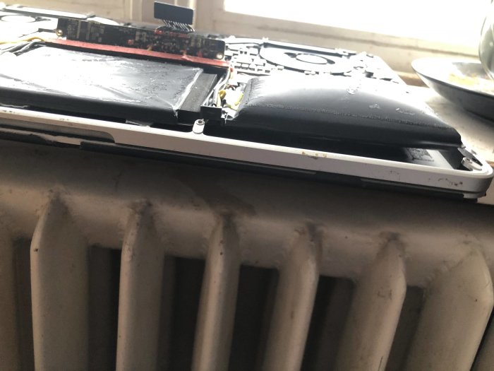 MacBook Pro med öppet chassi och svullet batteri som deformerat laptopens hölje.