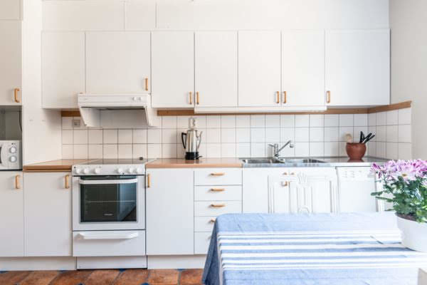 Välbevarat vitt kök med skåp, diskbänk och inbyggd ugn, redo för försäljning.