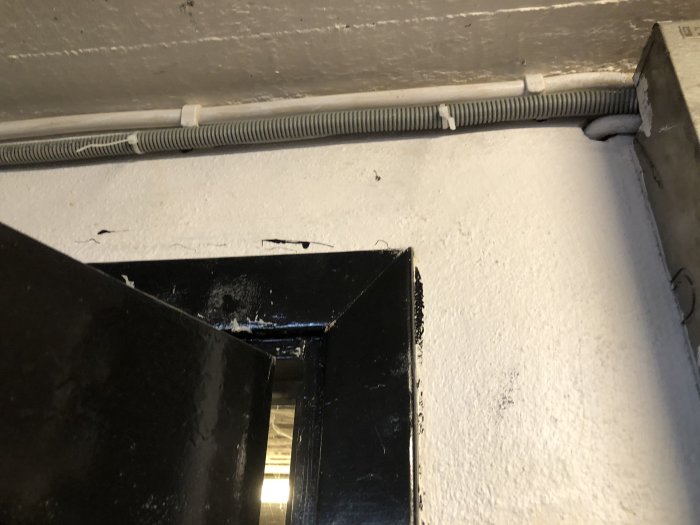 Oskyddade kablar dragna längs med en vägg vid en öppen genomföring.