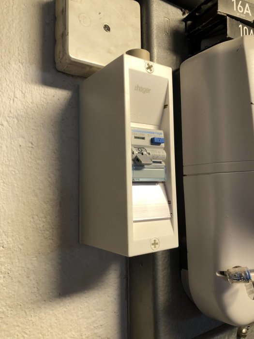 Elkoppling med jordfelsbrytare utan skyddande hölje på en vit vägg.