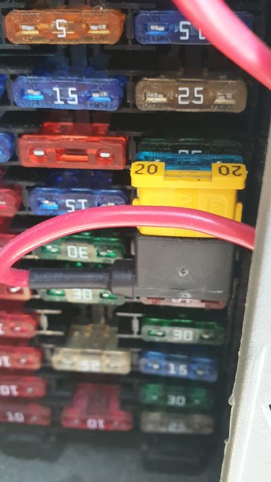Röd kabel ansluten till bilens säkringsbox som del av förlängningssladd installation.