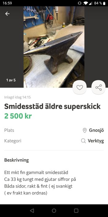 Gammalt smidessmäde på arbetsbänk i verkstad med verktyg i bakgrunden.