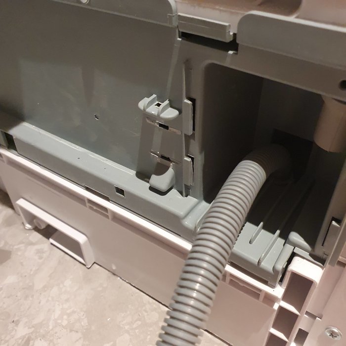 Delvis öppen Cylinda torktumlare med synlig slits på främre underdelen där det läcker vatten under drift.