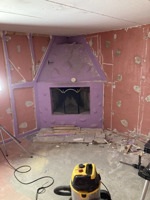 Renovering av källare med slipade väggar, påbörjad klinkersläggning och en dammsugare i förgrunden.