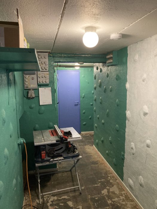 Källare under renovering med slipade väggar, gipsbruk, verktygsbord och ej lagt klinkergolv.