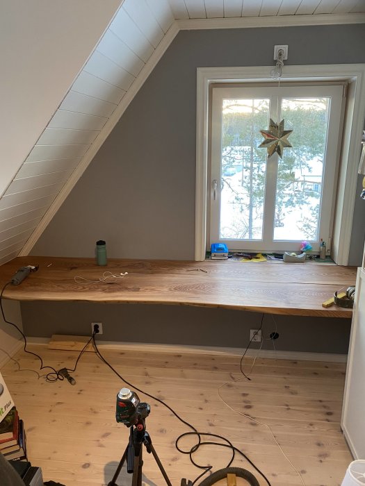 Nyinstallerad bänkskiva av alm i ett hemmakontors utrymme under snedtak med fönster och julstjärna.