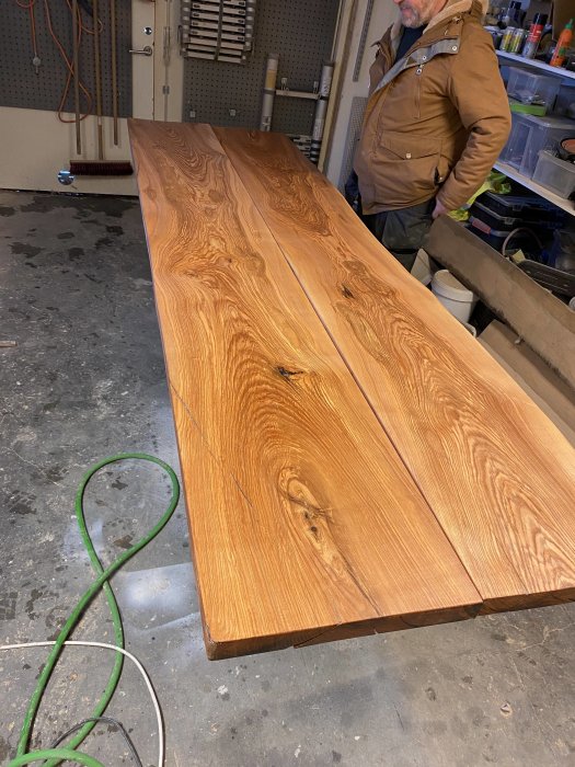 Hyvlad och slipad almträsbänkskiva i ett garage, med en person bredvid.