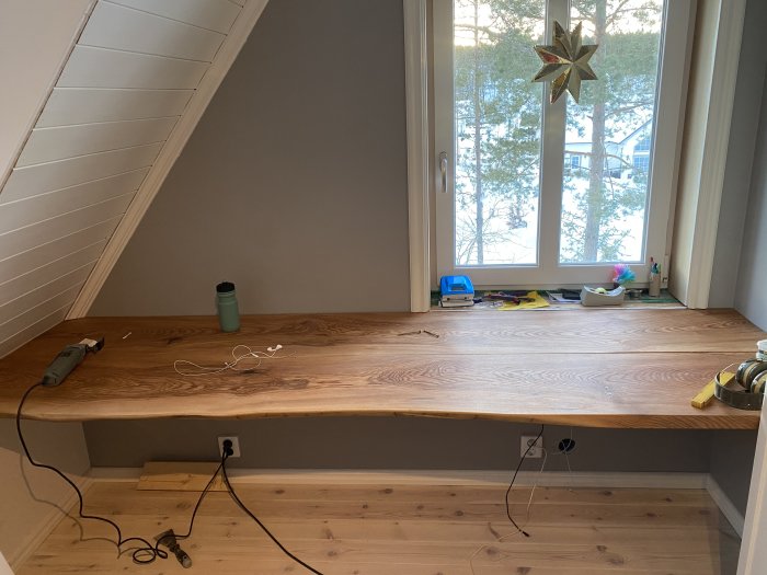 Nyhyvlad och slipsad almträbänkskiva i ett hemmakontor, verktyg och kablar synliga.