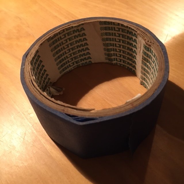 Rulle av blå maskeringstejp från Biltema på ett bord.