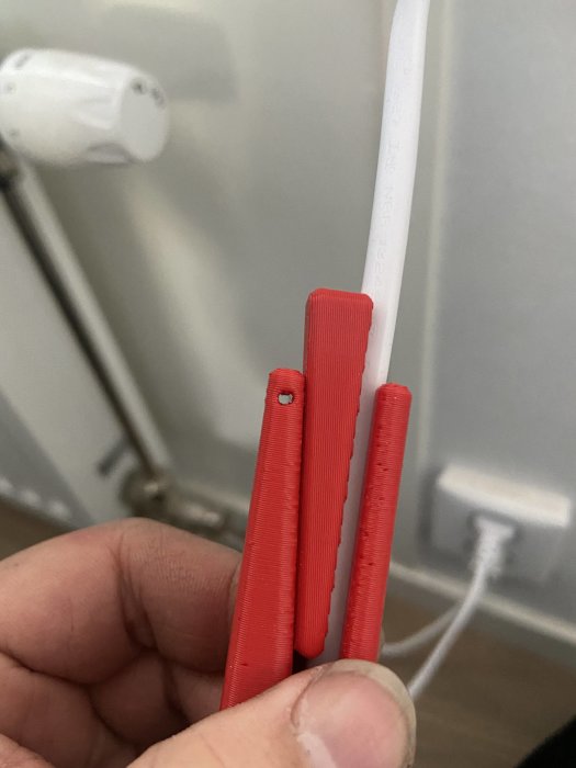 Hand håller röda 3D-utskrivna objekt som visar processen för spiralisering.