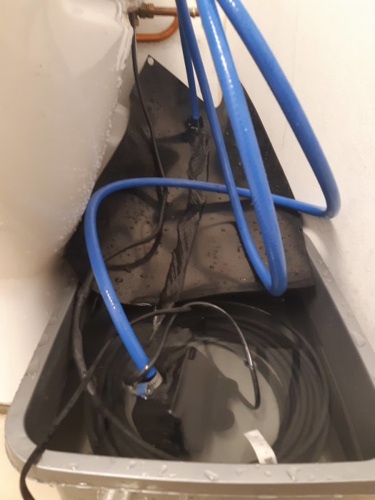 Vattenstenspump i plastlåda med varmvatten och blå slangar för att tina frusen PEM-slang.