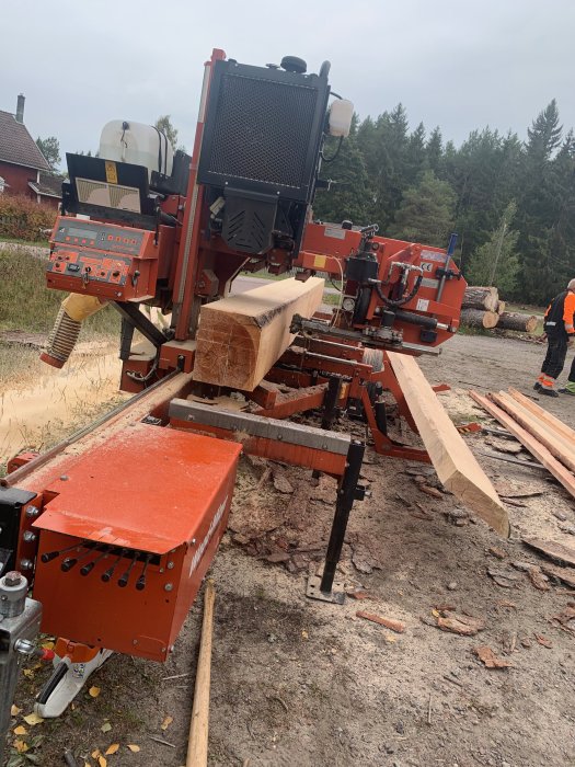 Ett mobilt sågverk i arbete som förvandlar en stock till plank och brädor utomhus.