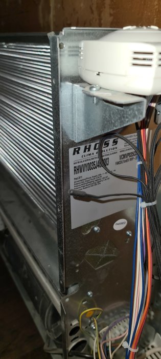 En fläktkonvektor från Rhoss tillverkad 2011 med informationsetikett och elektriska kablar synlig.