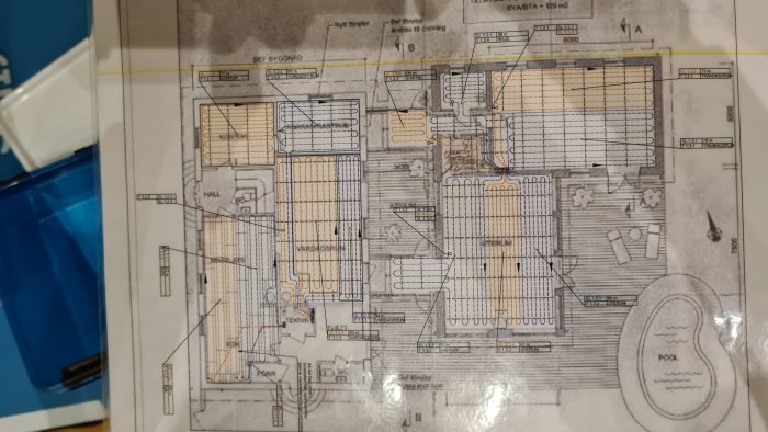 Ritning av husplan som visar layout och installation av golvvärme, markerade områden indikerar värmeslingor.