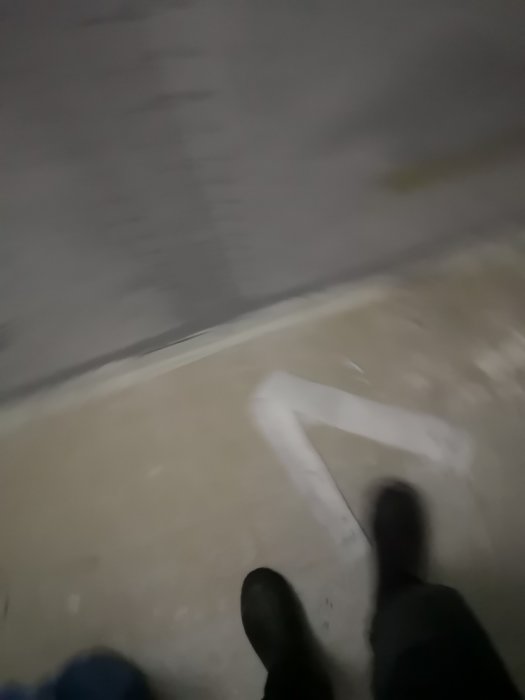 Oskarp bild på en person i mörkret med fokus på vit linje på marken, sannolikt relaterad till byggprojekt.