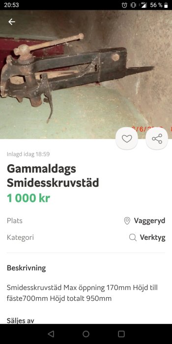 Gammaldags smidesskruvstäd i metall med långt handtag och robust konstruktion, använt skick.