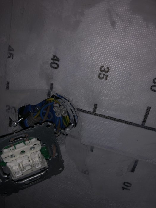 Öppen elinstallation med trådar i tom dosa på nytt tätskikt med mätmärken.